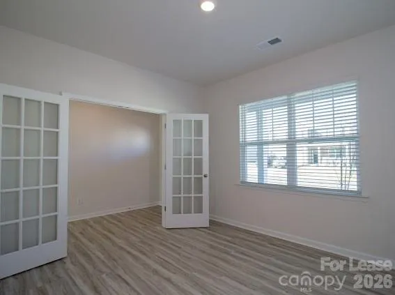 an empty room with wooden floor and windows