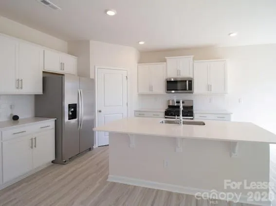 a large kitchen with cabinets wooden floor and stainless steel appliances