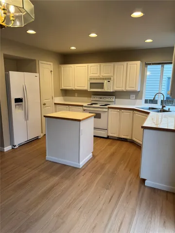 a kitchen with stainless steel appliances granite countertop a white cabinets a sink a stove a refrigerator and island