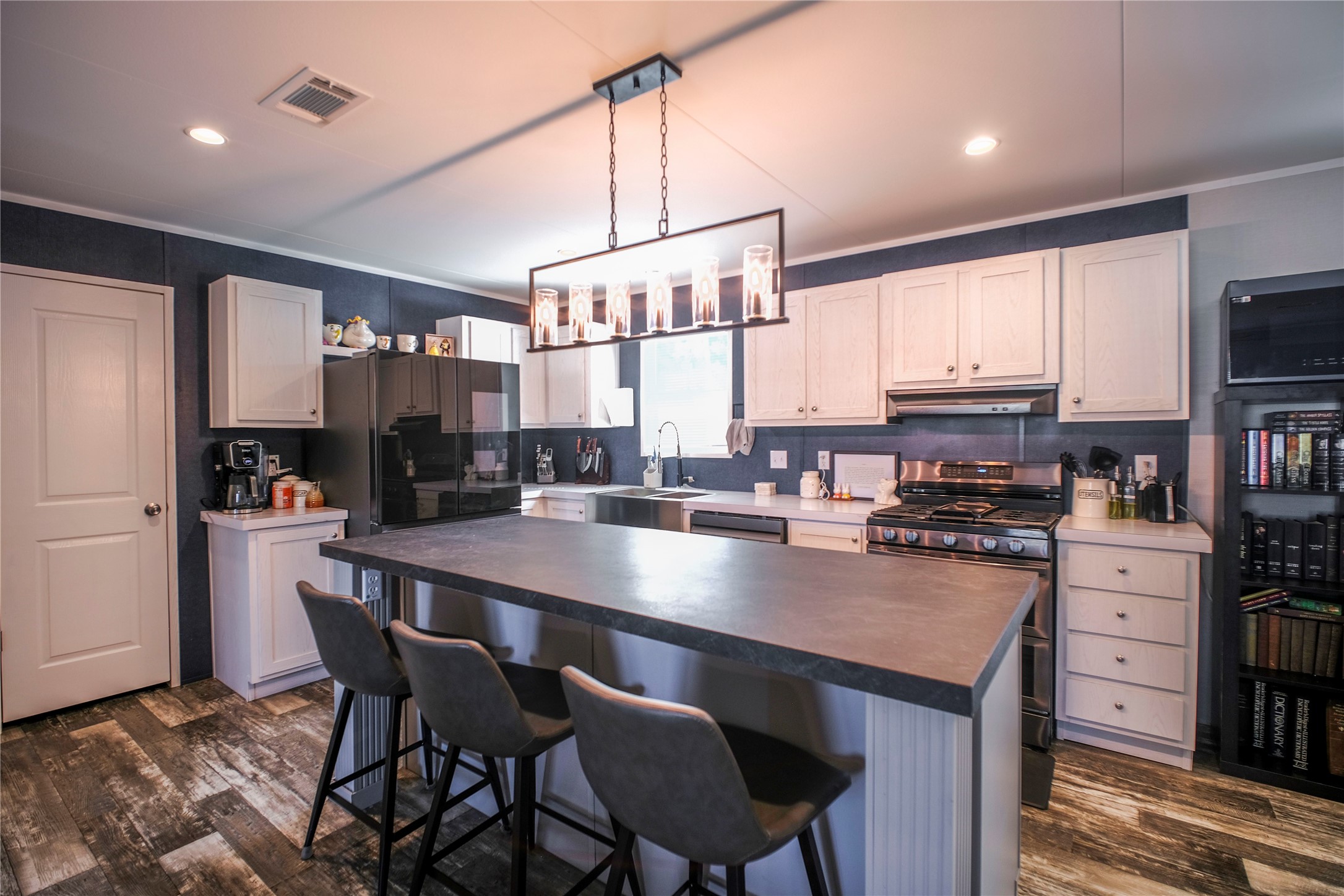 5402 Five Oaks Drive Spring, TX 77389 - Photo 5 of 20 a open kitchen with stainless steel appliances granite countertop a stove a refrigerator a kitchen island a sink dishwasher and white cabinets with wooden floor