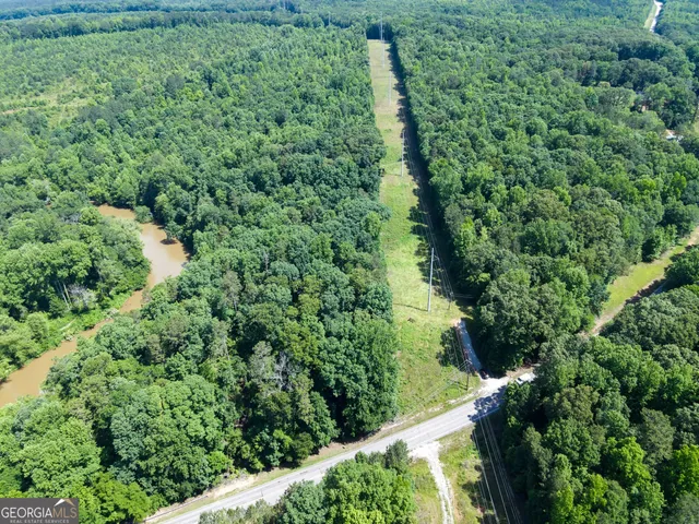 an aerial view of residential house with outdoor space and trees all around
