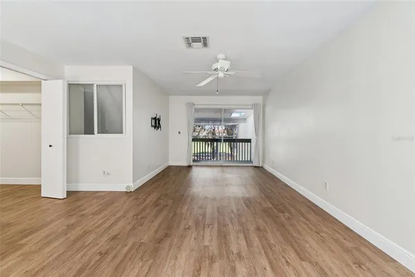 a view of a room with wooden floor and a chandelier fan