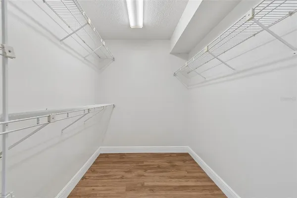 an empty room with wooden floor cabinet and windows