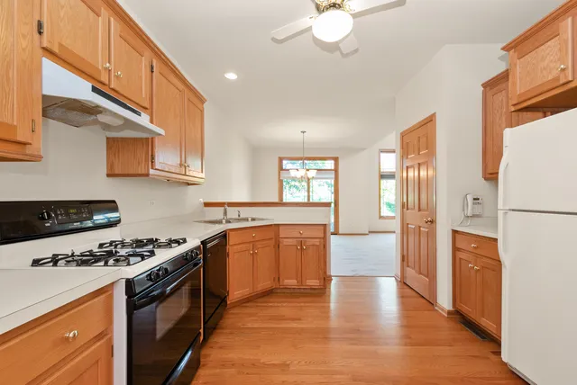 a kitchen with stainless steel appliances granite countertop a stove a sink dishwasher and a refrigerator with white cabinets