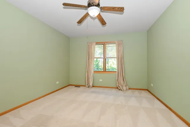 an empty room with chandelier fan and windows