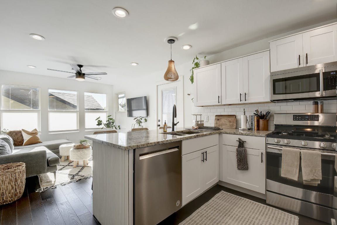 2901 Glen Rae Street, Unit A Austin, TX 78702 - Photo 3 of 36 a kitchen with stainless steel appliances granite countertop a stove top oven a sink dishwasher and white cabinets with wooden floor