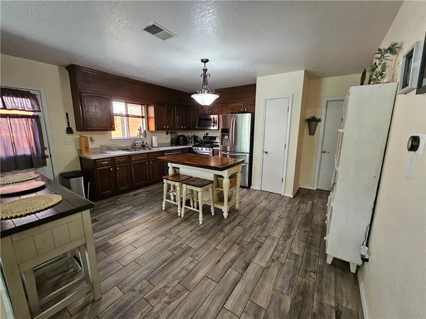 a kitchen with stainless steel appliances granite countertop a sink a stove and a wooden floors
