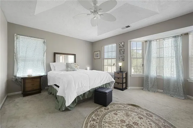a bed sitting in a spacious bedroom next to a window and a chandelier