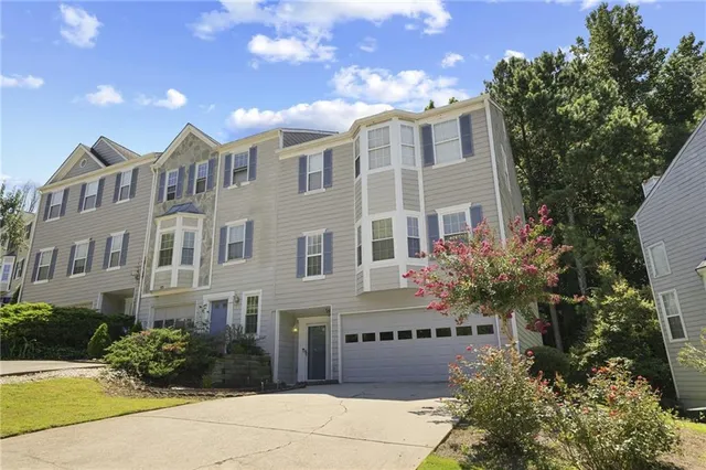 a front view of a multi story residential apartment building with yard and parking