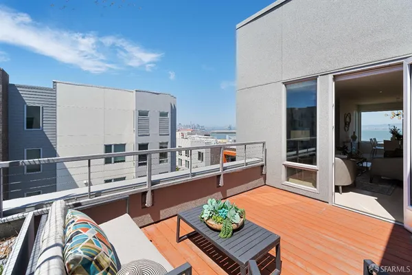 a living room with stainless steel appliances furniture a rug and a kitchen view