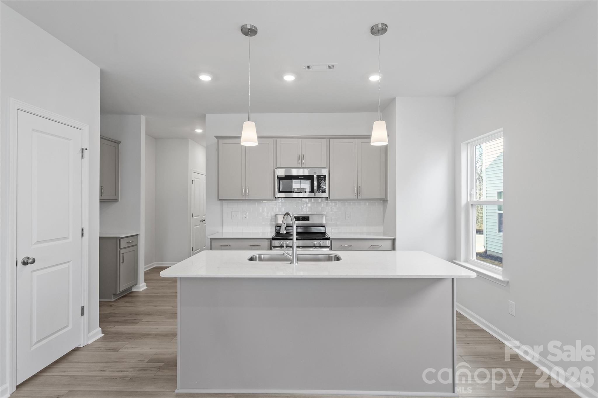 a view of a kitchen with kitchen island a sink stainless steel appliances and cabinets