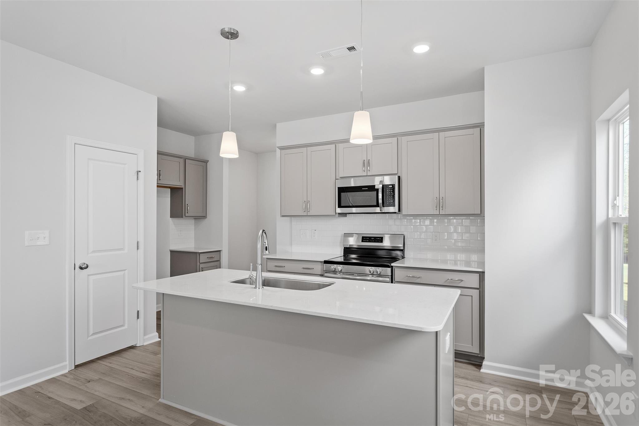 5865 Tuckaseegee Road, Unit 2 Charlotte, NC 28208 - Photo 3 of 26 a kitchen with stainless steel appliances a sink stove refrigerator and white cabinets with wooden floor