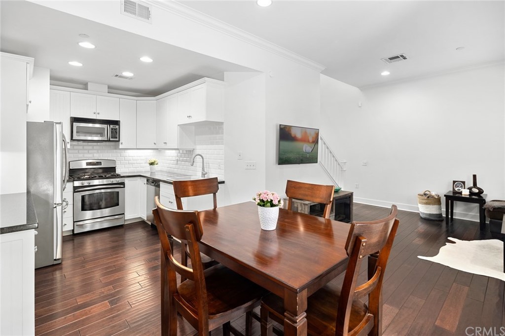 a open dining room with stainless steel appliances kitchen island a table and chairs