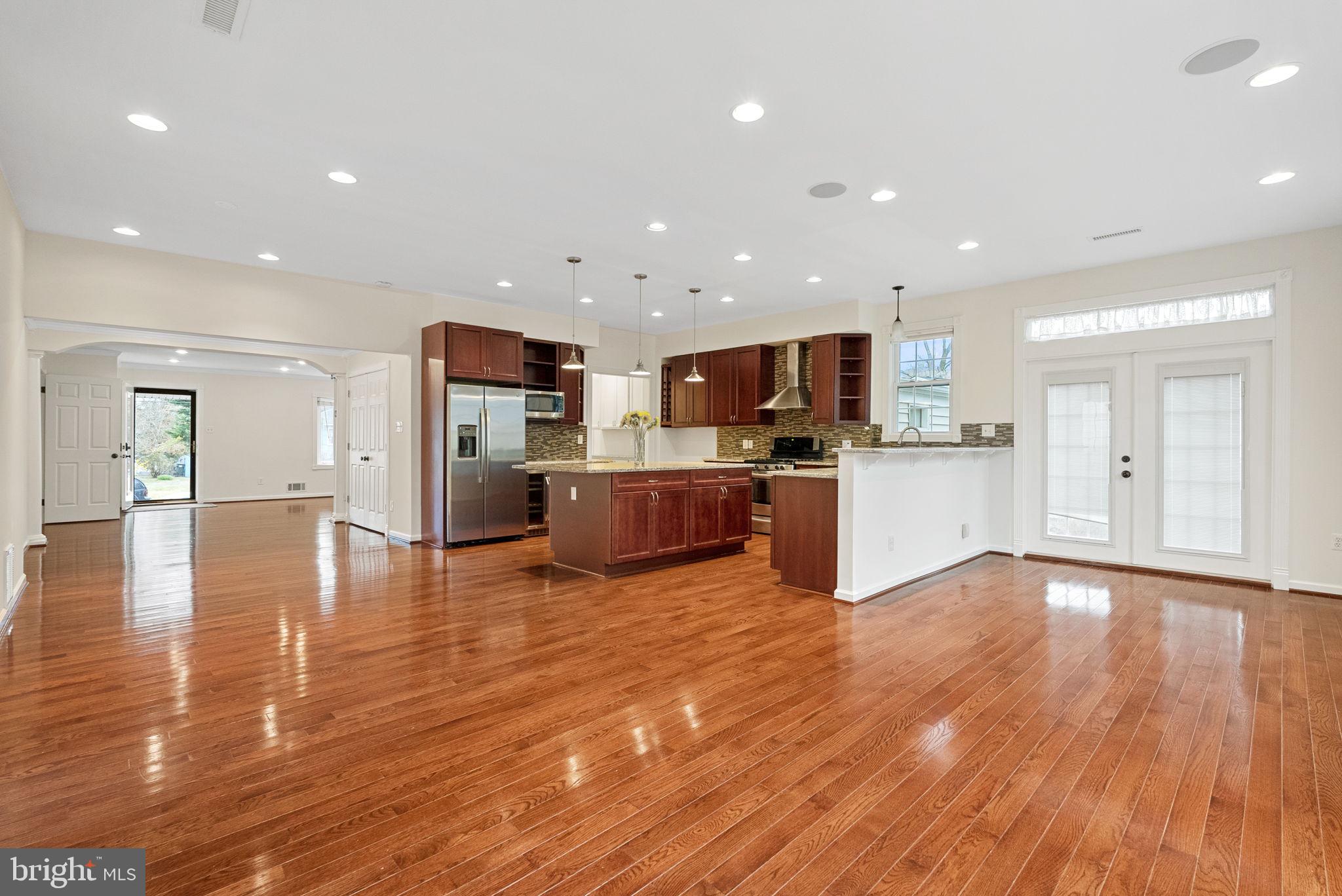 a view of kitchen with kitchen island wooden floor and stainless steel appliances
