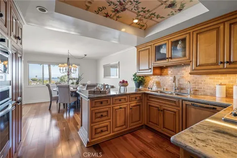 a kitchen with stainless steel appliances granite countertop a stove top oven a sink dishwasher a dining table and chairs with wooden floor