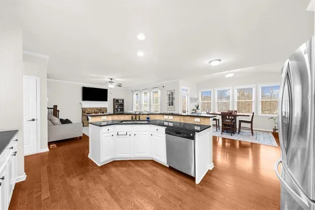 a kitchen with stainless steel appliances granite countertop a sink dishwasher stove and white cabinets with wooden floor