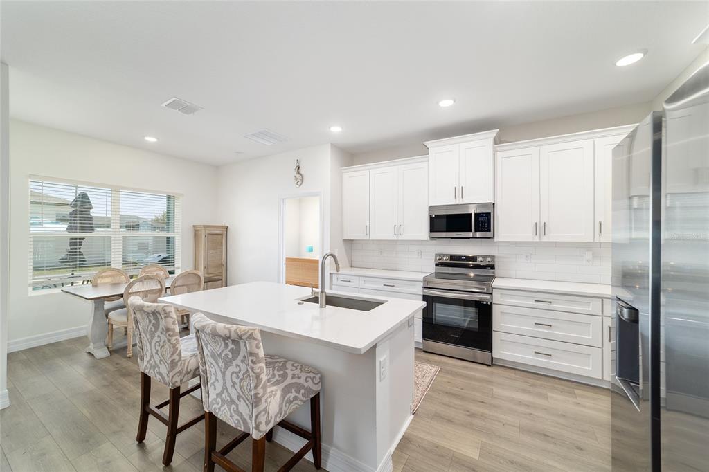 4838 Southwest 130th Street Ocala, FL 34473 - Photo 14 of 48 a kitchen with stainless steel appliances granite countertop a stove top oven a sink dishwasher a dining table and chairs with wooden floor