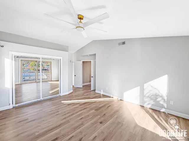 a view of empty room with wooden floor and fan