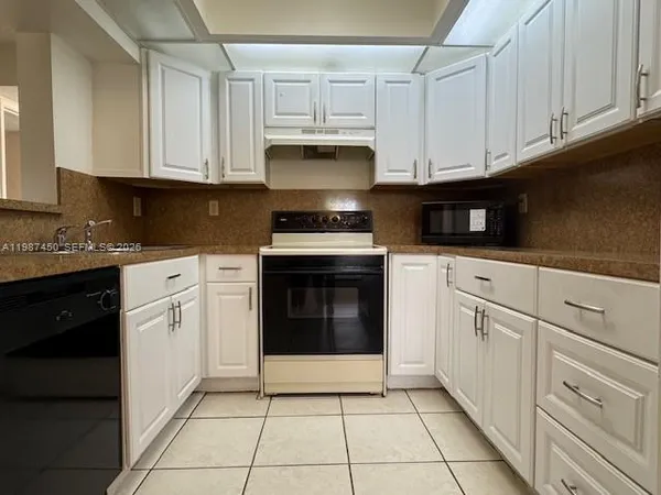 a kitchen with granite countertop white cabinets and stainless steel appliances