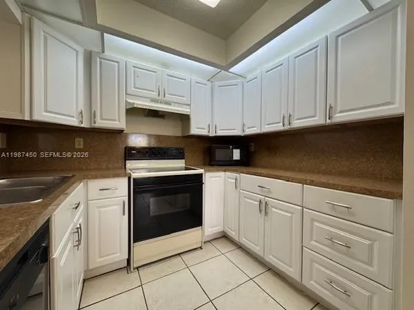 a kitchen with granite countertop white cabinets and stainless steel appliances