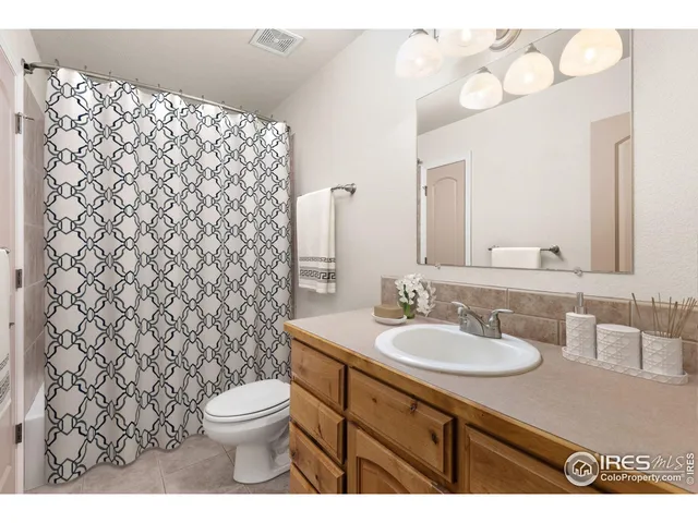 a bathroom with a granite countertop toilet sink mirror and shower