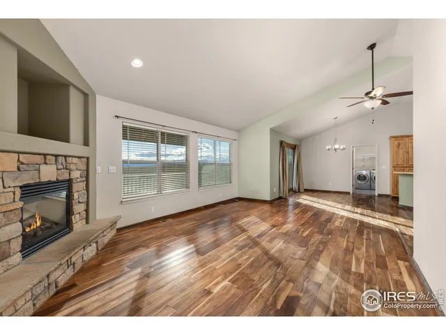a view of an empty room with wooden floor fireplace and a window