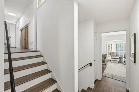 a view of a hallway with wooden floor and staircase