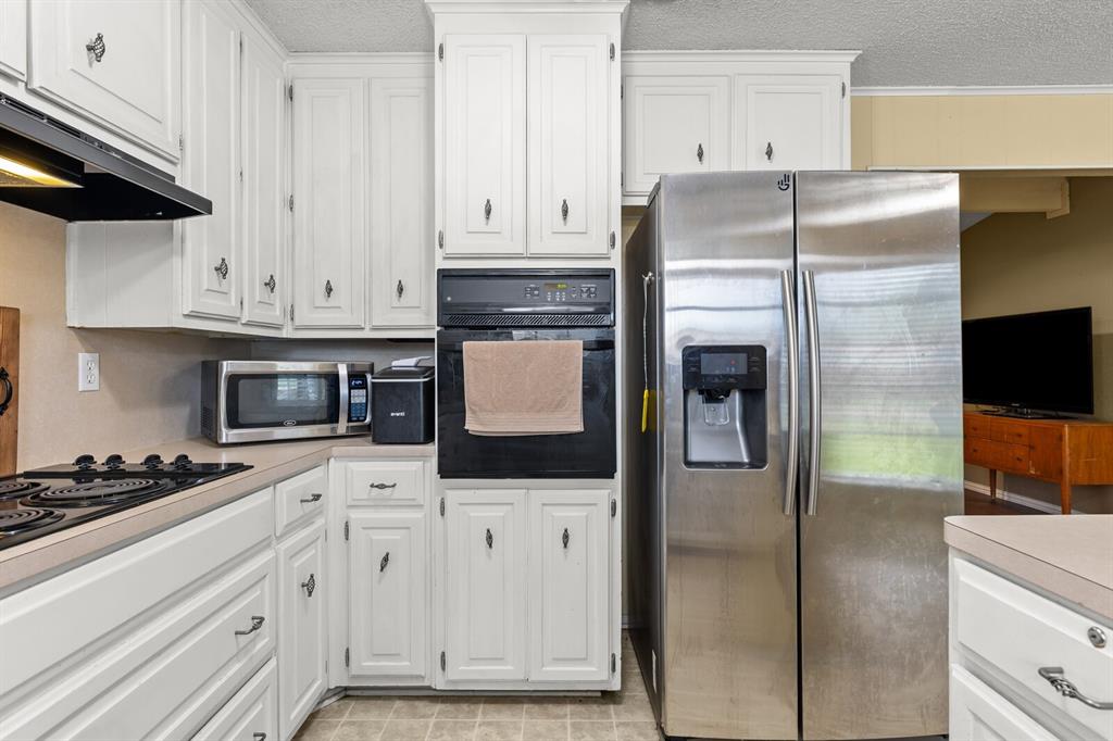 505 Pinewood Lane Hewitt, TX 76643 - Photo 3 of 38 Kitchen featuring white cabinetry with dark hardware, a built-in oven, and a stainless-steel side-by-side refrigerator