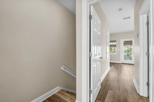 a view of a hallway with wooden floor and a bathroom