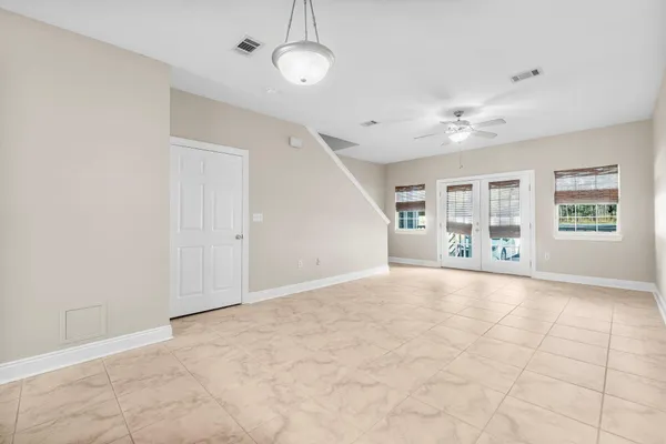 an empty room with chandelier fan and windows