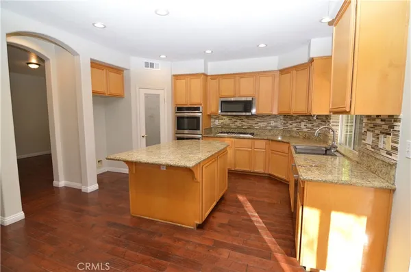 a kitchen with stainless steel appliances granite countertop a sink a stove and a refrigerator