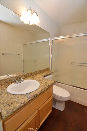 a bathroom with a granite countertop sink toilet and a mirror