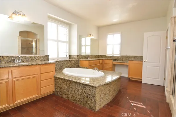 a spacious bathroom with a granite countertop sink a mirror and a bathtub