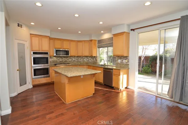 a large kitchen with stainless steel appliances granite countertop a stove a sink and a refrigerator