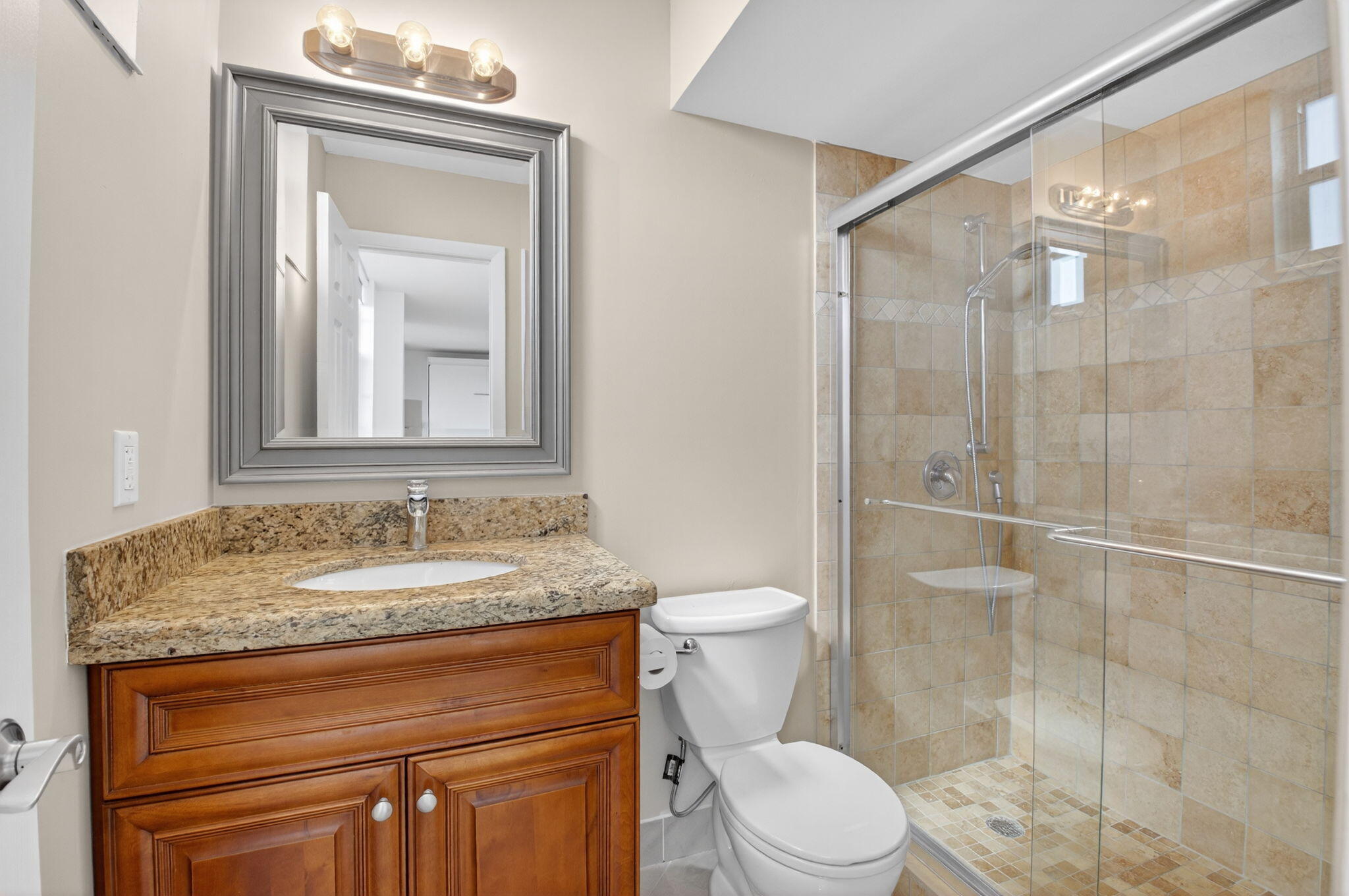 5500 Northwest 2nd Avenue, Unit 718 Boca Raton, FL 33487 - Photo 18 of 34 a bathroom with a granite countertop sink toilet a mirror and shower