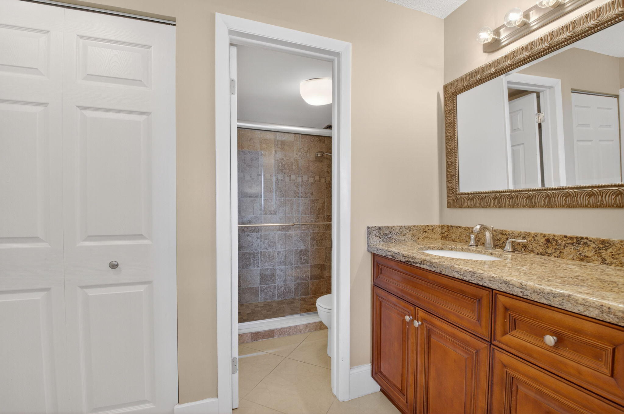 5500 Northwest 2nd Avenue, Unit 718 Boca Raton, FL 33487 - Photo 22 of 34 a bathroom with a granite countertop sink a mirror and a shower