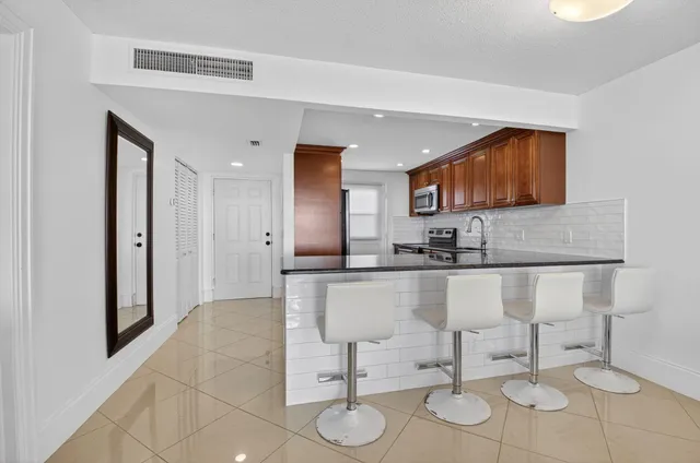 a kitchen with stainless steel appliances kitchen island granite countertop a sink and a refrigerator