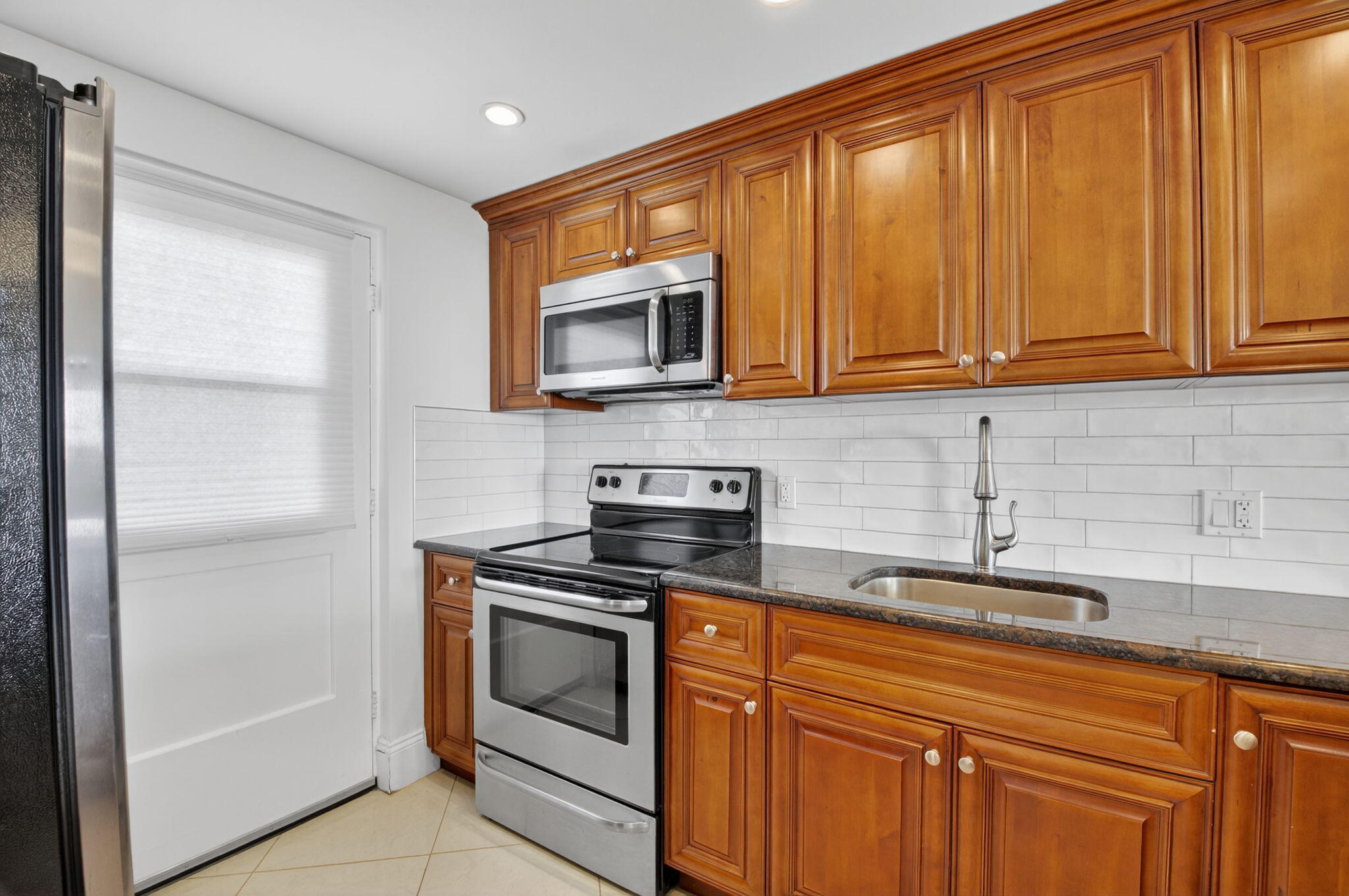 5500 Northwest 2nd Avenue, Unit 718 Boca Raton, FL 33487 - Photo 8 of 34 a kitchen with stainless steel appliances granite countertop a sink stove and microwave