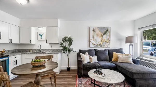 a living room with stainless steel appliances kitchen island granite countertop furniture a rug kitchen view and a window