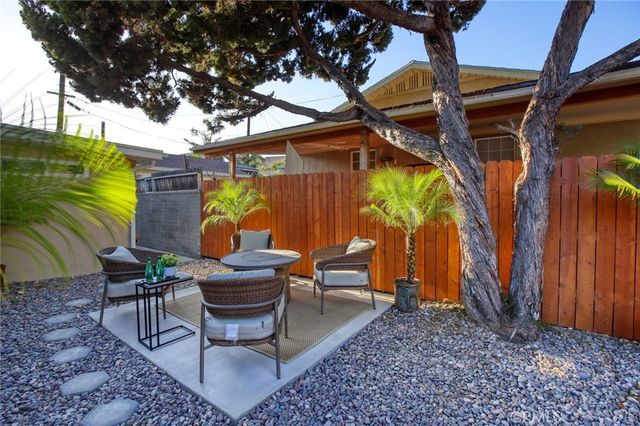 a view of a backyard with table and chairs potted plants and tree