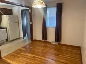an empty room with wooden floor and kitchen view