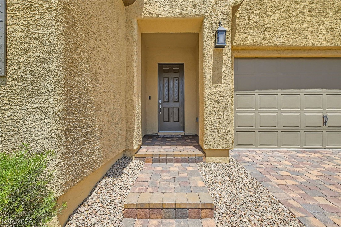 498 Pebble Run Avenue Henderson, NV 89011 - Photo 3 of 47 A welcoming paver walkway leads to the recessed entry of this desert-style home with an attached garage.