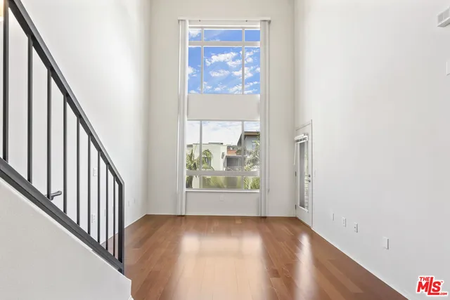 a view of an empty room with wooden floor and windows