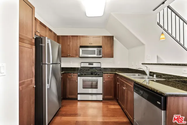 a kitchen with stainless steel appliances granite countertop a refrigerator a stove a sink and a microwave