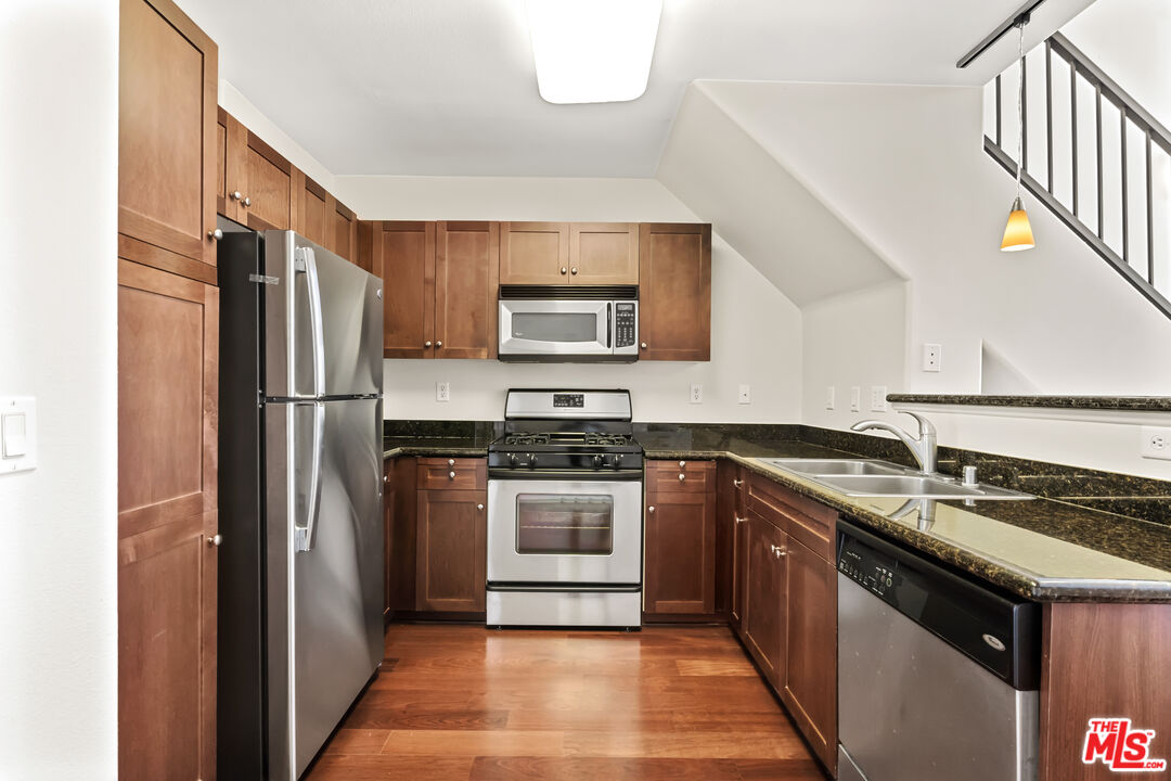 100 South Alameda Street, Unit 418 Los Angeles, CA 90012 - Photo 3 of 32 a kitchen with stainless steel appliances granite countertop a refrigerator a stove a sink and a microwave