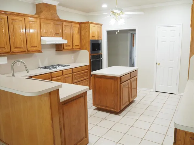 a kitchen with stainless steel appliances a sink a stove a refrigerator cabinets and a dining table