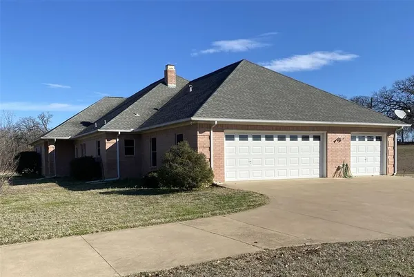 a front view of house with yard and trees in the background