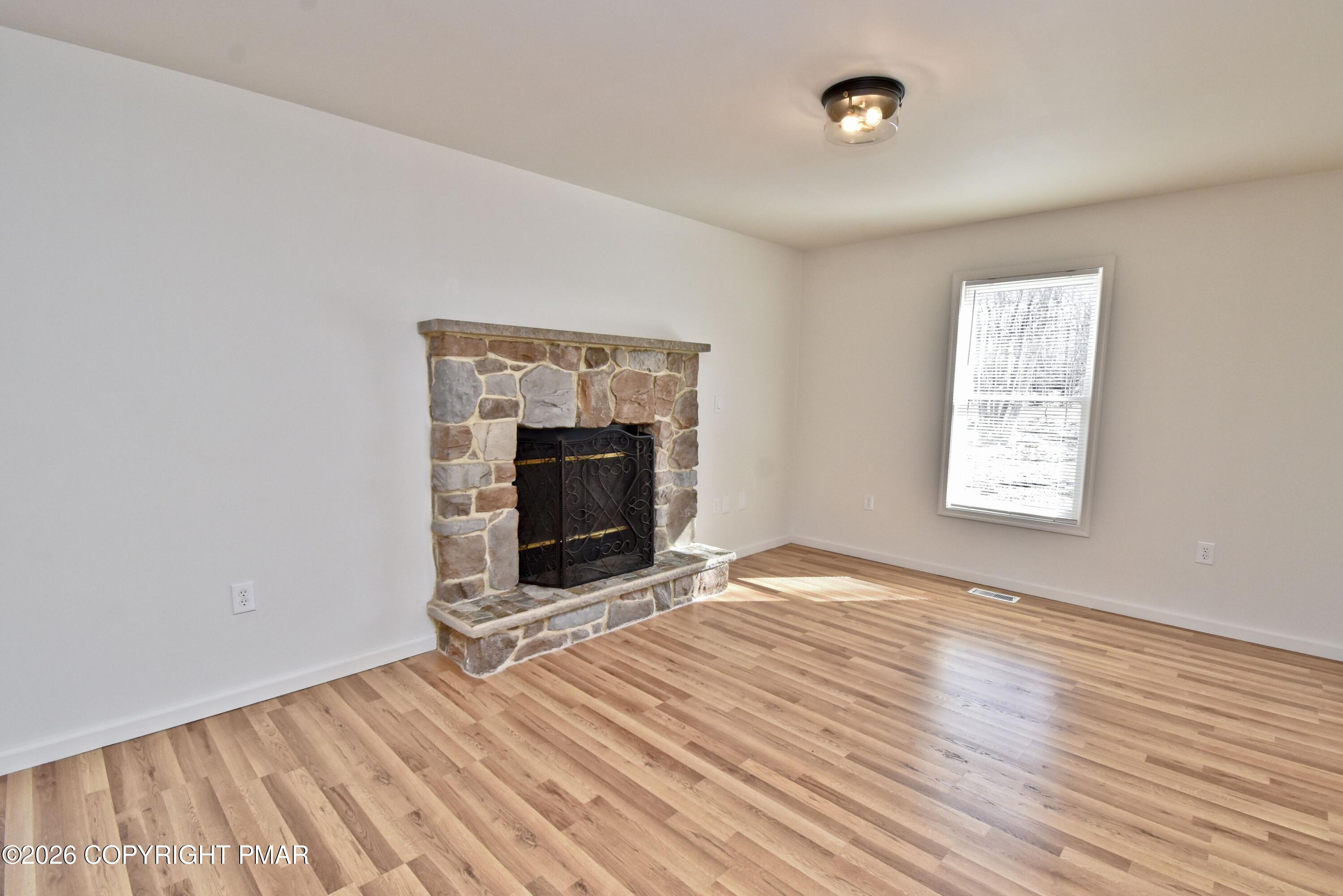108 Pipher Road Bushkill, PA 18324 - Photo 9 of 50 an empty room with wooden floor a fireplace and windows