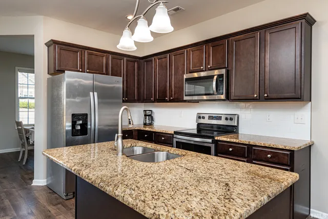 a kitchen with stainless steel appliances granite countertop a sink refrigerator and microwave