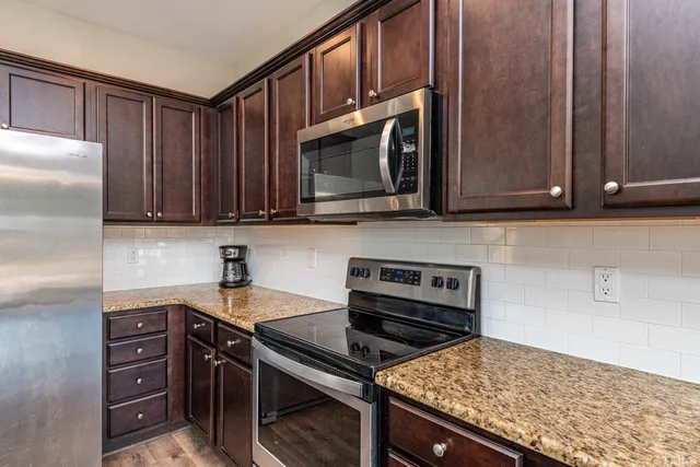 a kitchen with granite countertop a stove microwave and refrigerator